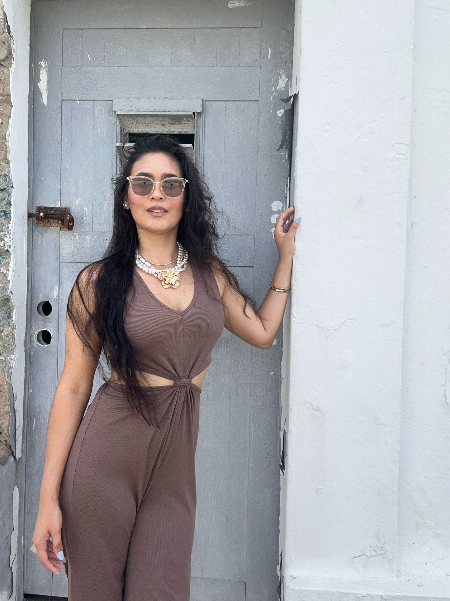 Woman in a brown dress standing in front of a gray door.