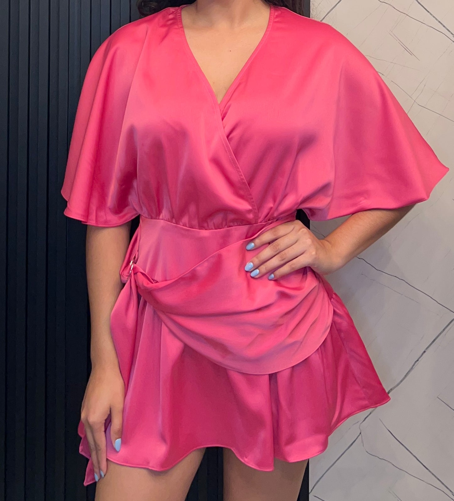 Person wearing a pink satin dress against a neutral background