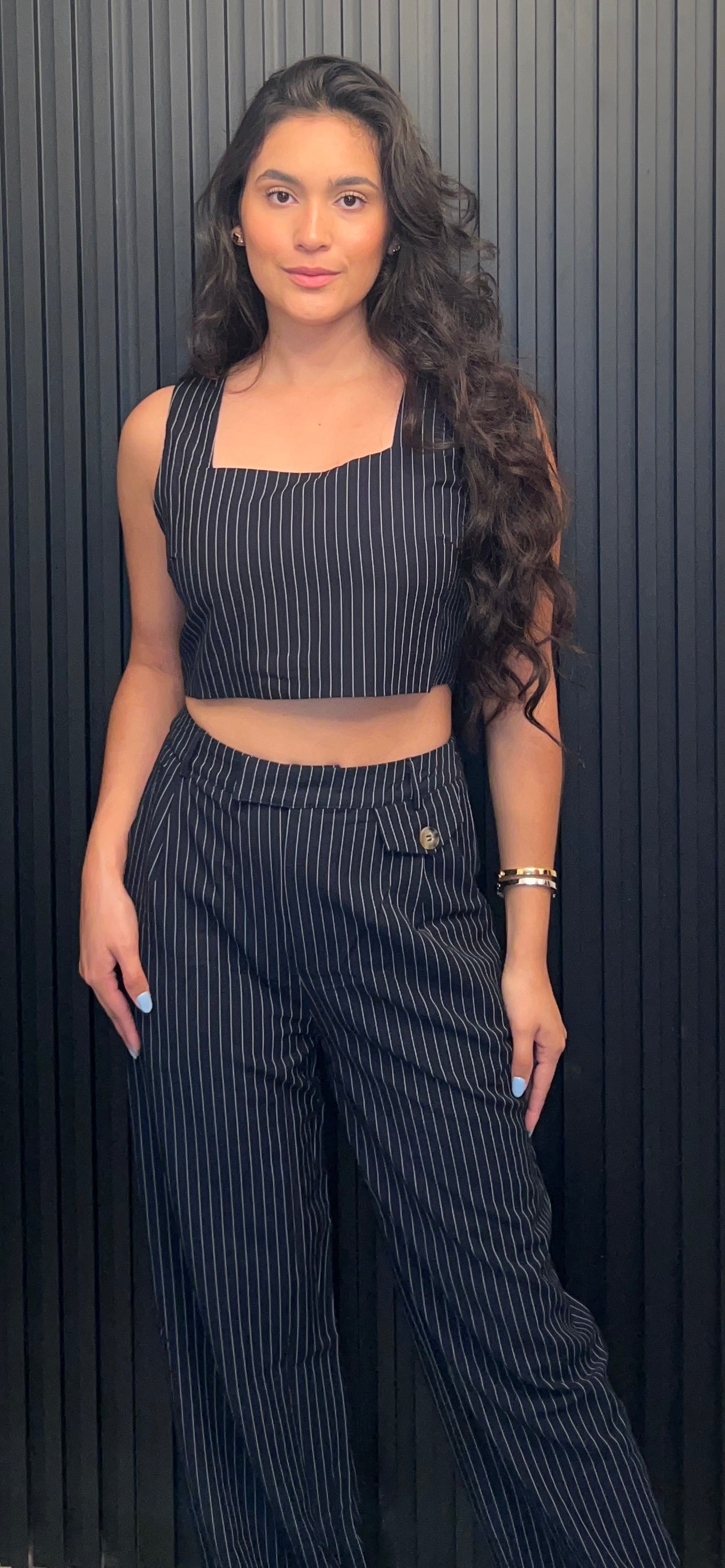 Woman wearing a black pinstripe outfit against a dark background