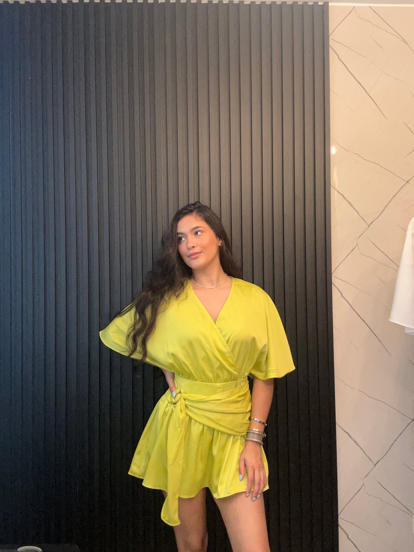 Person wearing a yellow dress standing on a black platform with a tiled floor background